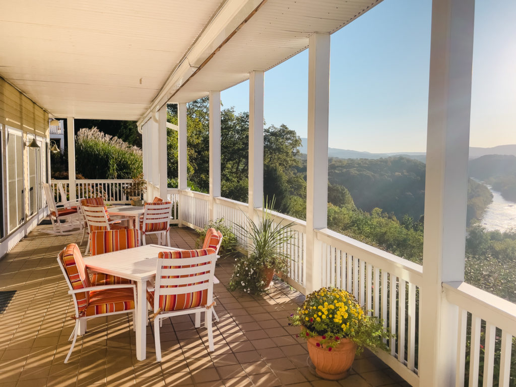 tables and chairs on porch with landscape
