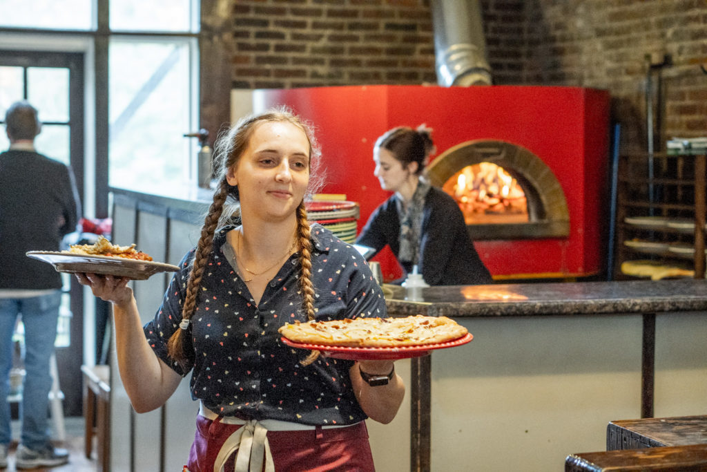 girl server with pizza in restaurant